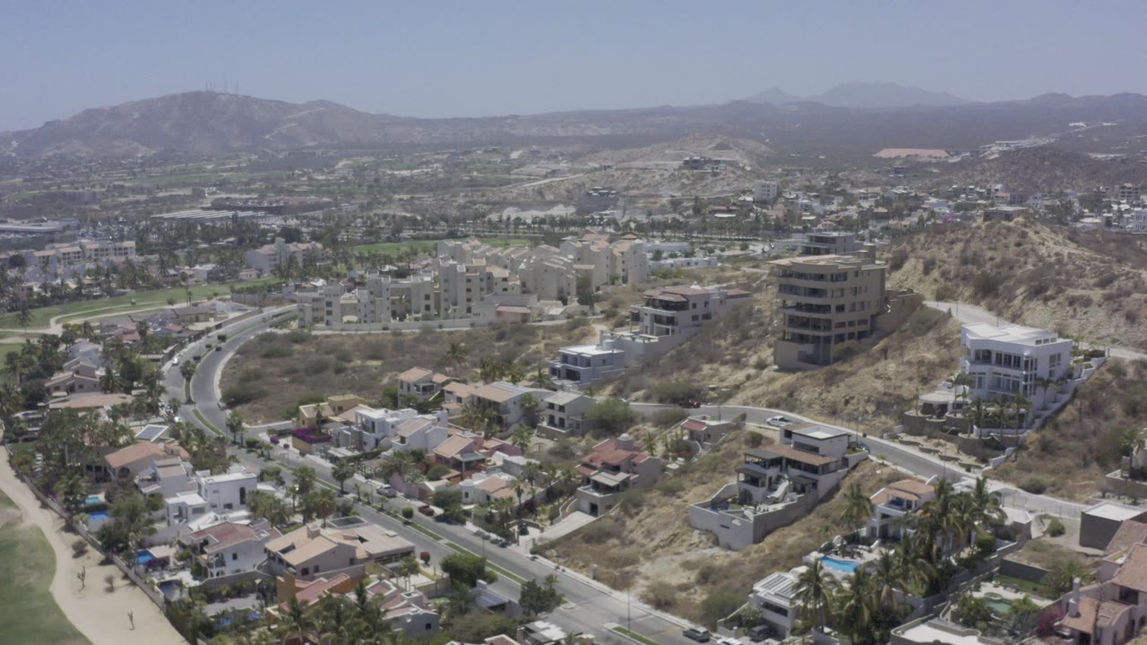 Aerial neighborhood view with homes, a hilltop building, and roads.