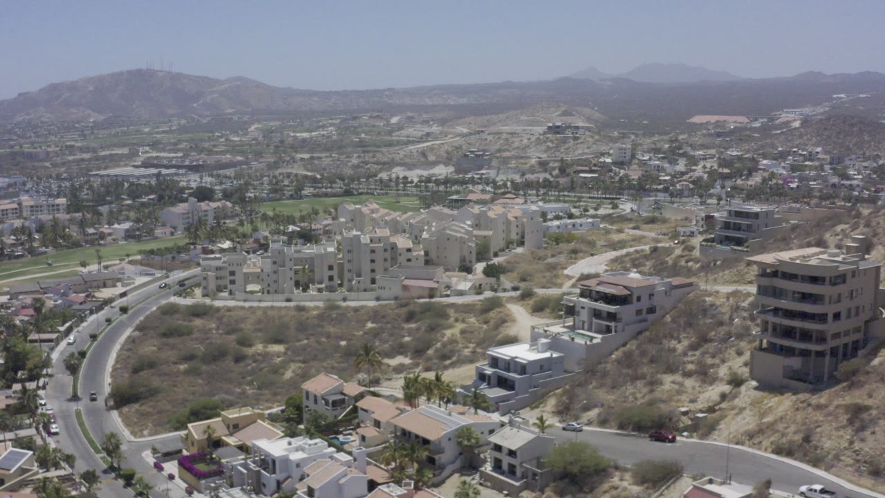 Aerial view of roads, homes, apartment blocks, open fields, and distant hills