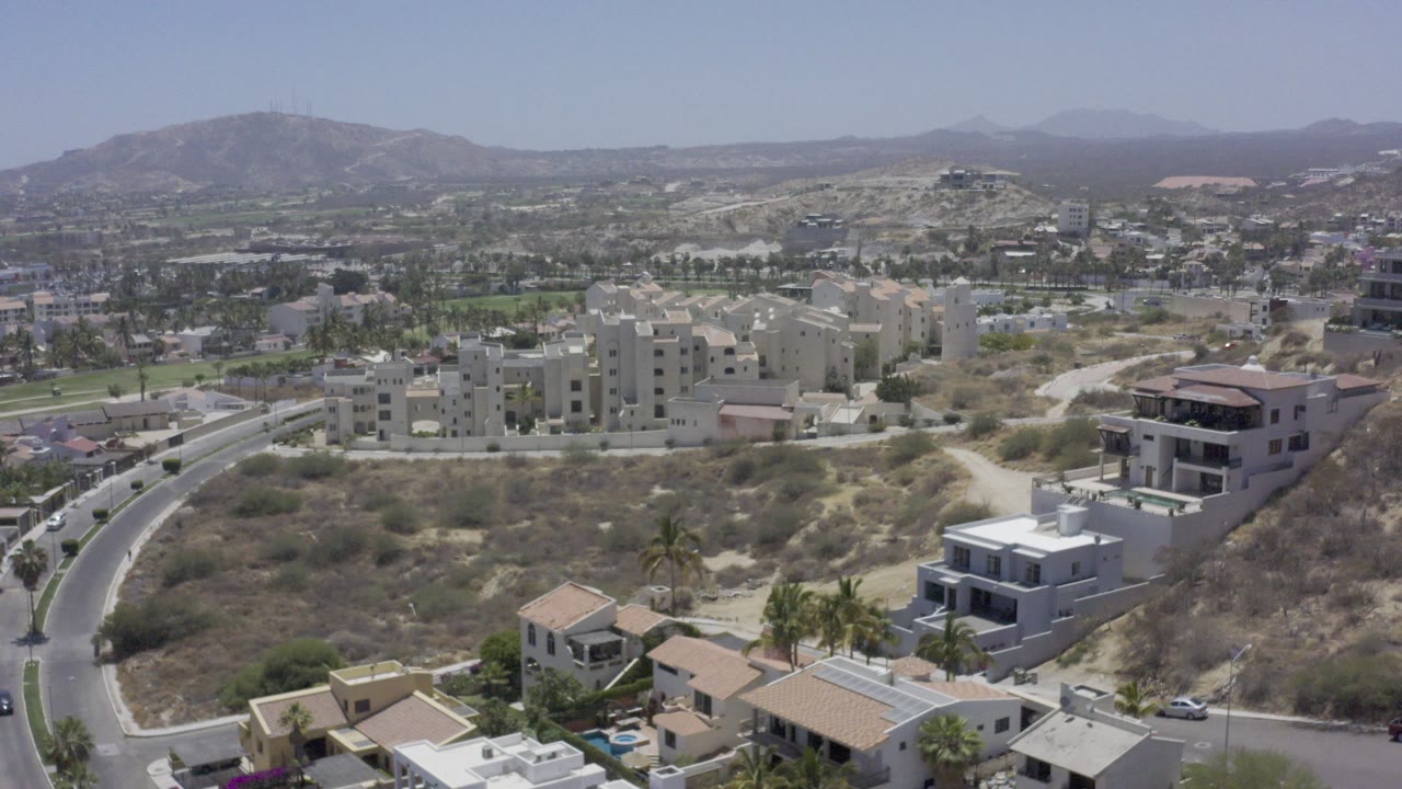 Aerial view of hillside homes, roads, palms, and distant mountains