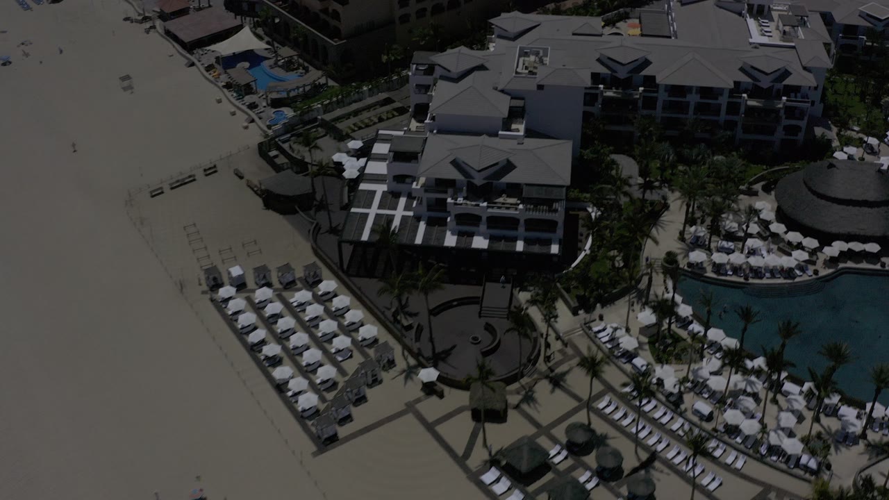 Aerial view of resort buildings beside an empty beach and swimming pool