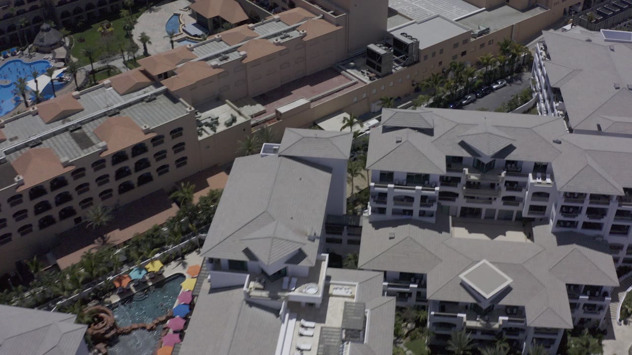 Overhead view of rooftops, courtyards, pools, and multi-story buildings.