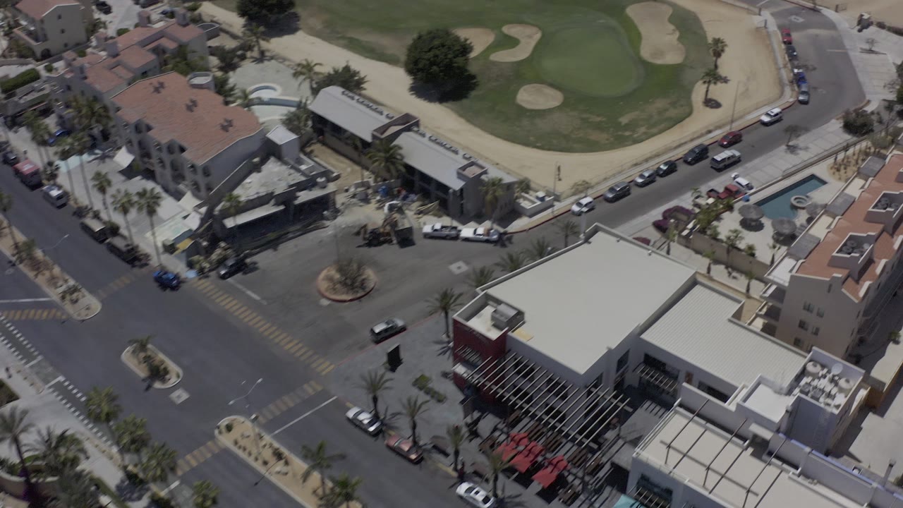 Aerial town block with a golf course and parked cars along the road.