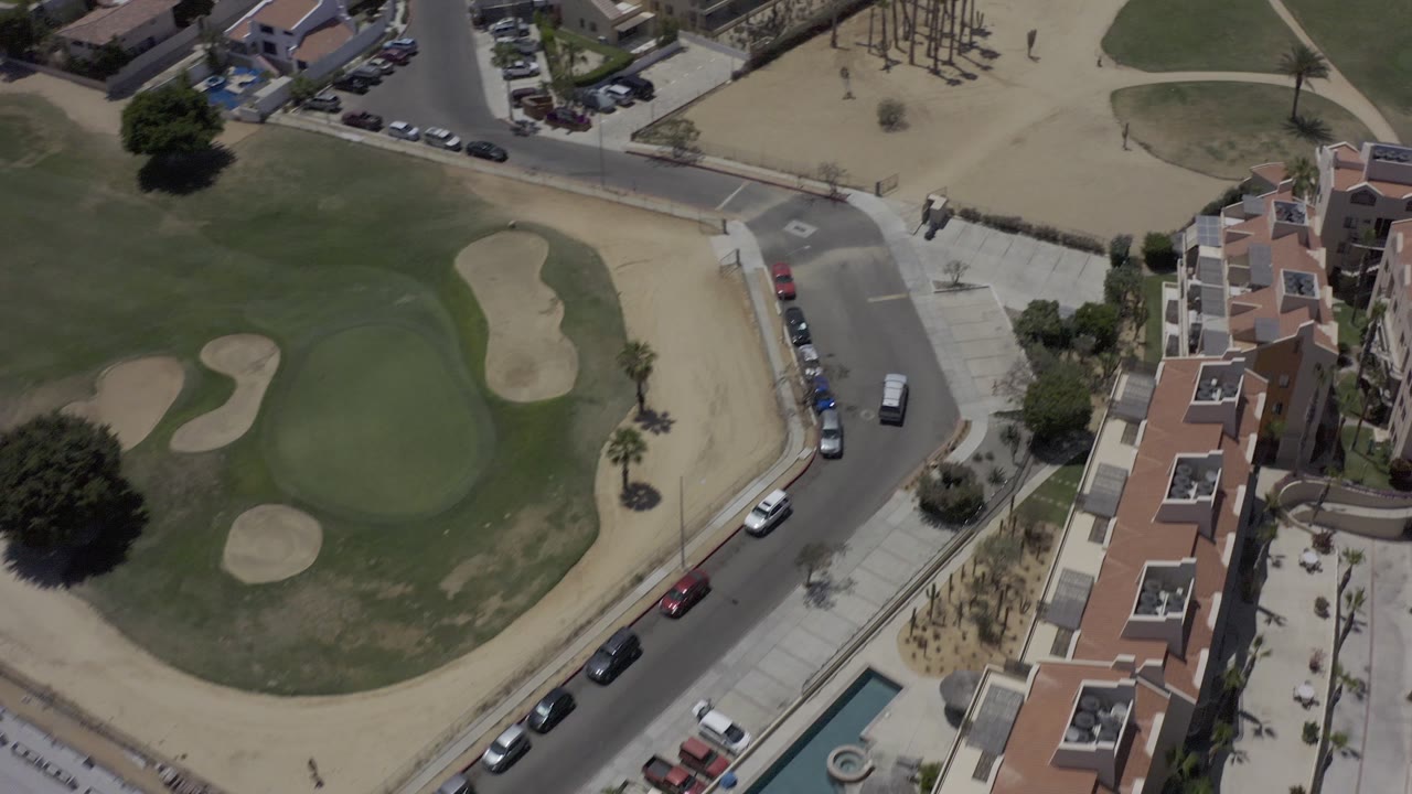 Drone view of a housing complex beside a green and dry open field.
