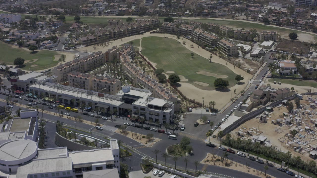 Aerial view of a golf course beside roads and buildings.