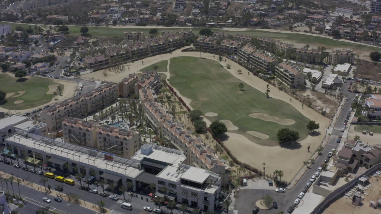 Aerial view of a green course bordered by residential buildings and streets.