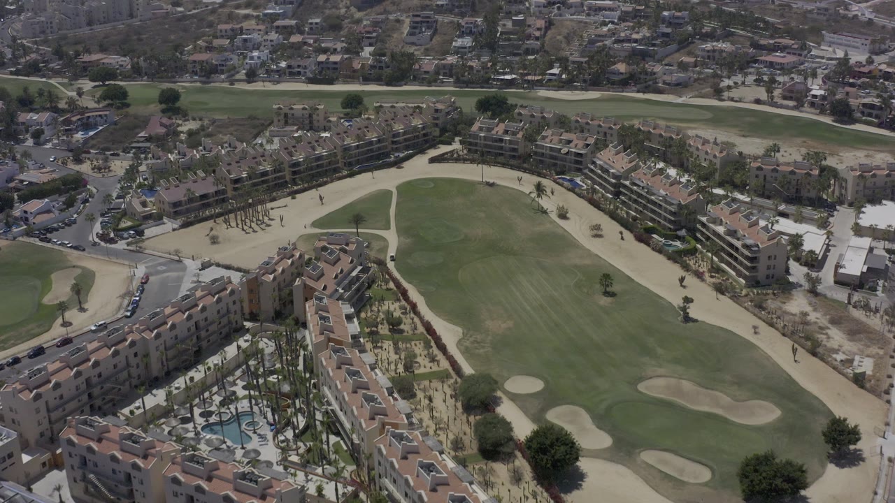 Drone-style overhead view of a golf fairway bordered by vacation rentals and roads.