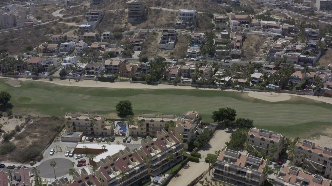 Aerial view of a golf fairway, villas, roads, and hillside homes.