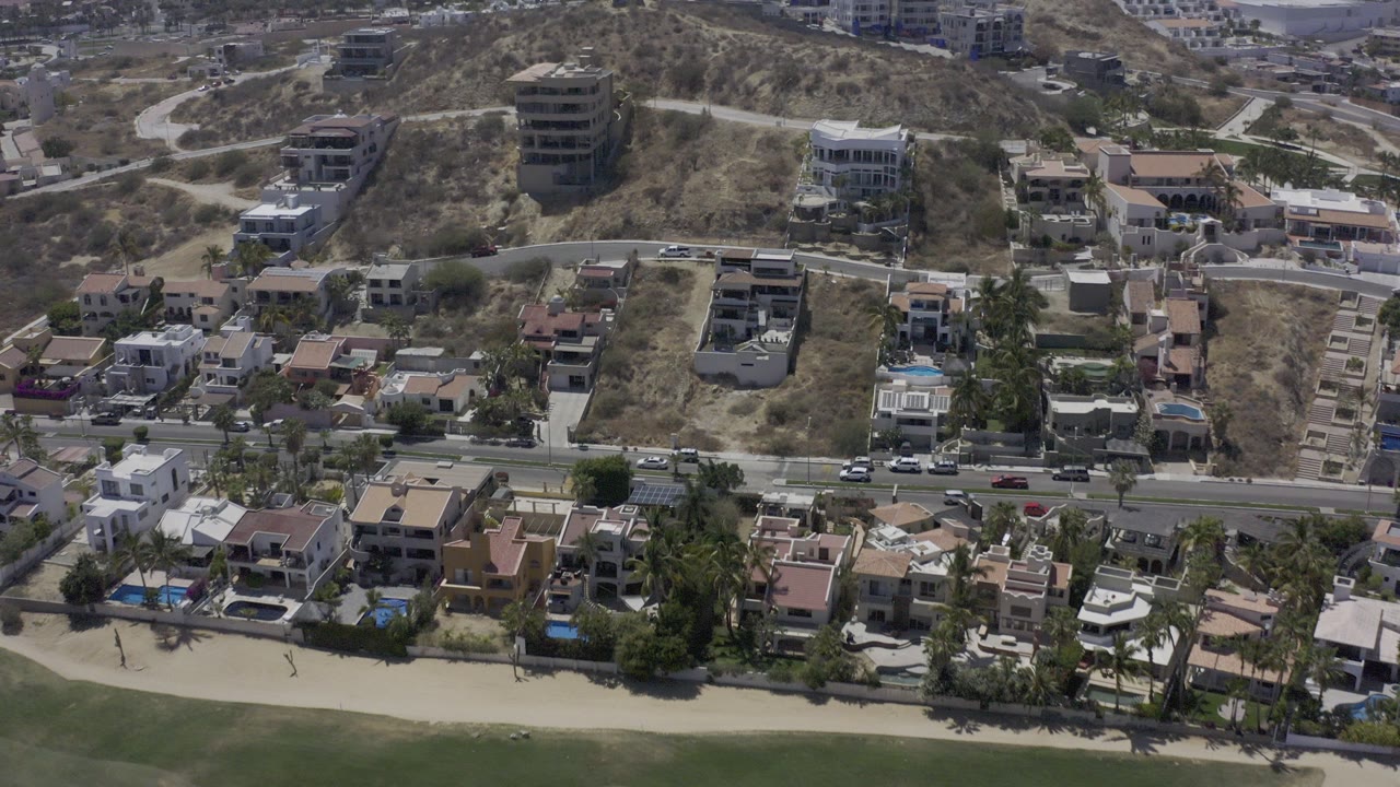 Aerial view of hillside homes, a road, and beach edge