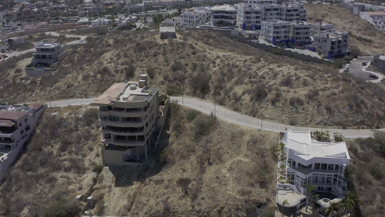 Dry residential hillside with homes and distant buildings.