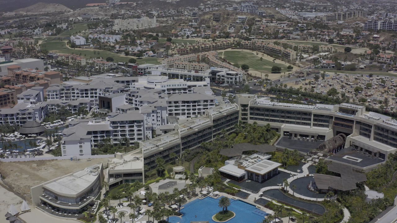 Aerial view of a modern building complex with pools and hillside development.