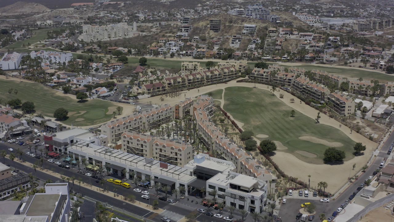Aerial view of streets, buildings, and a golf course beside hillside neighborhoods