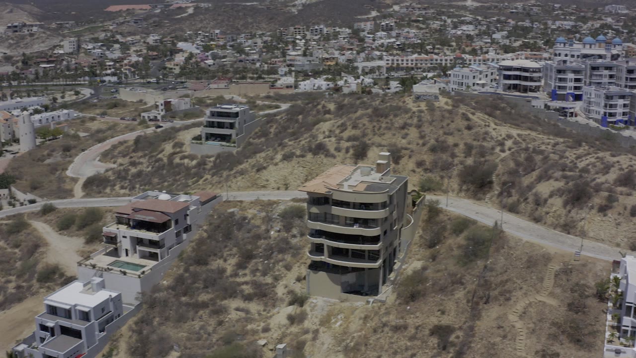 Aerial view across a dry ridge with hillside homes and city buildings.