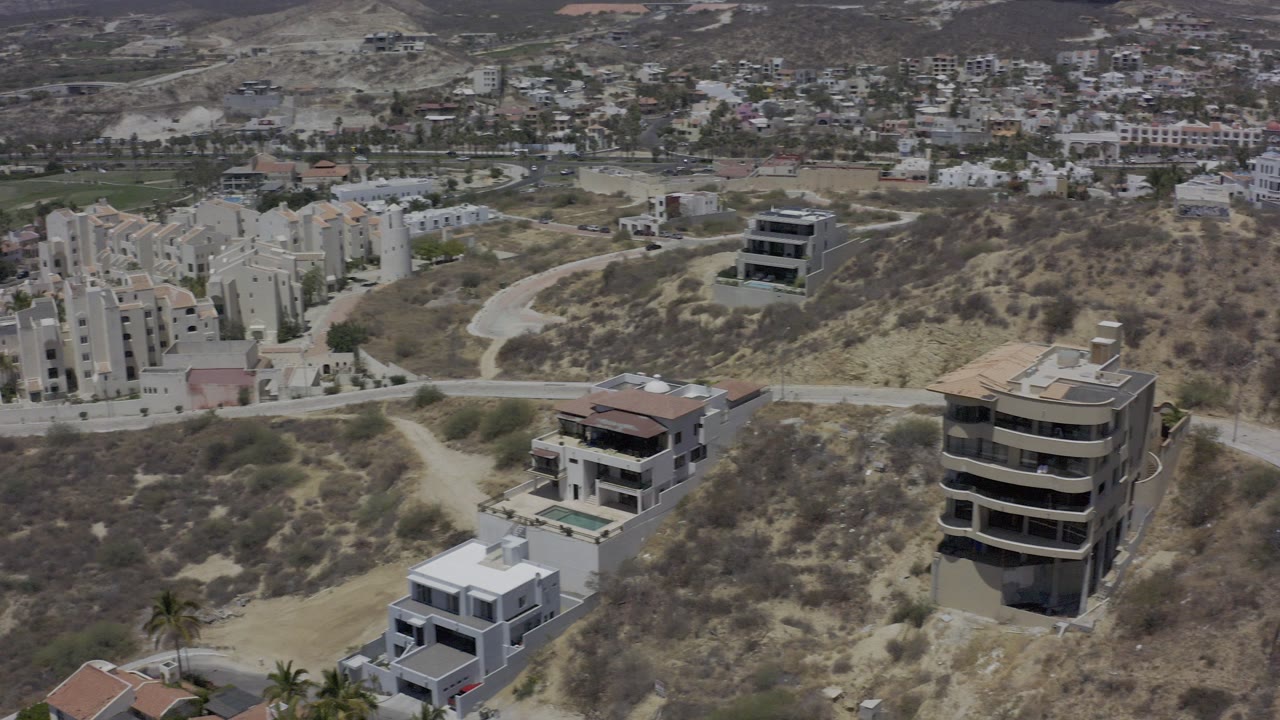 Aerial view of hillside homes and apartment buildings beside dry terrain.