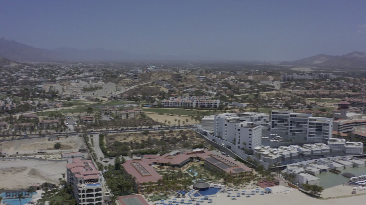 High aerial view over a desert valley community with buildings and distant mountains.