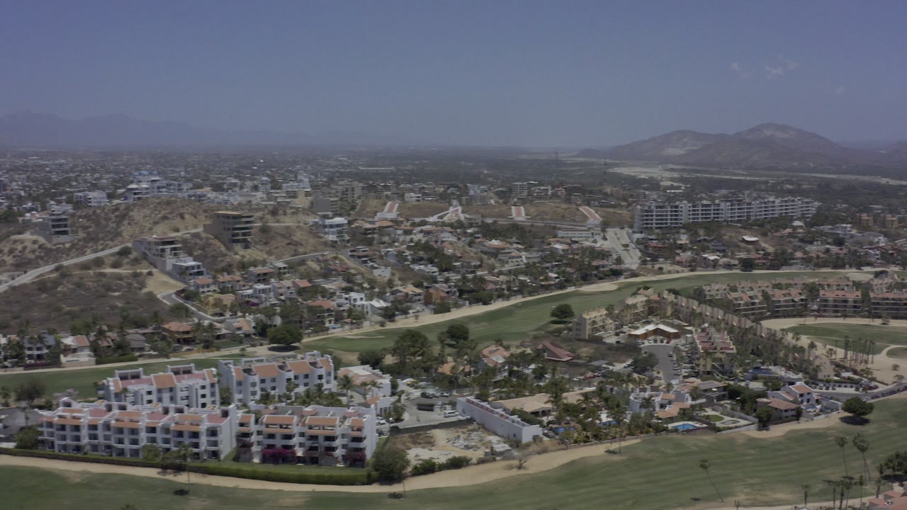Aerial view over homes, hotels, golf course, and distant mountains.