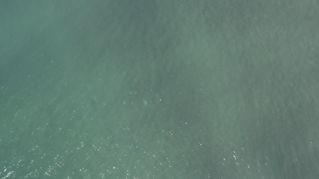 Top-down view of teal ocean water in Los Cabos, Mexico at the opening moment, with faint ripples and no visible people.