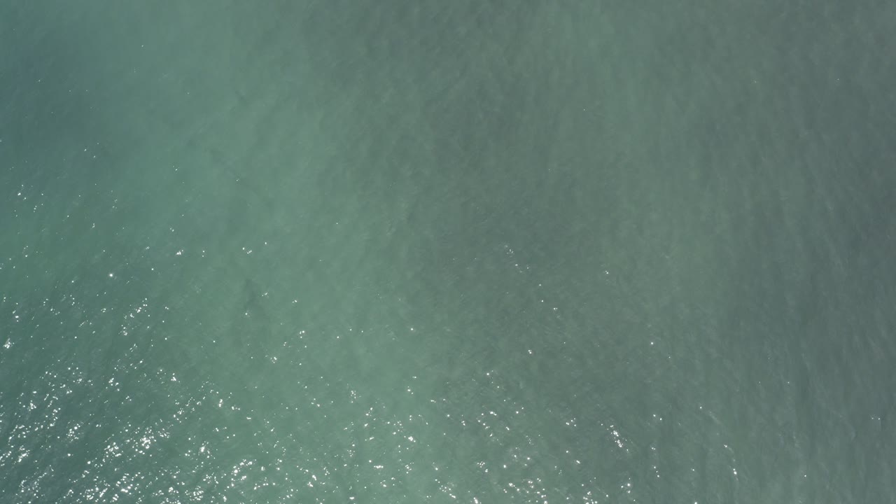 Opening frame of blue-green ocean water in Los Cabos, Mexico, with small bright glints across the upper-left ripples and no visible people.