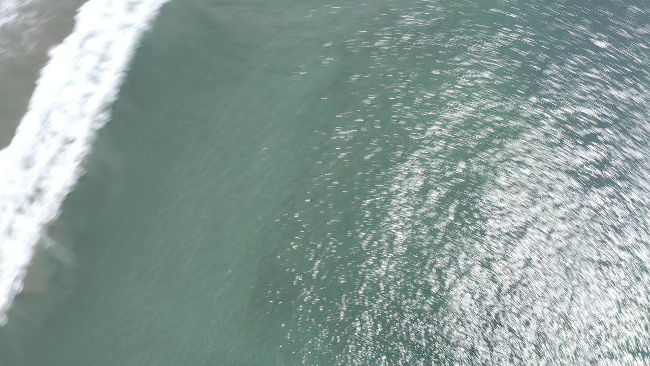 White surf line crossing green water from above.