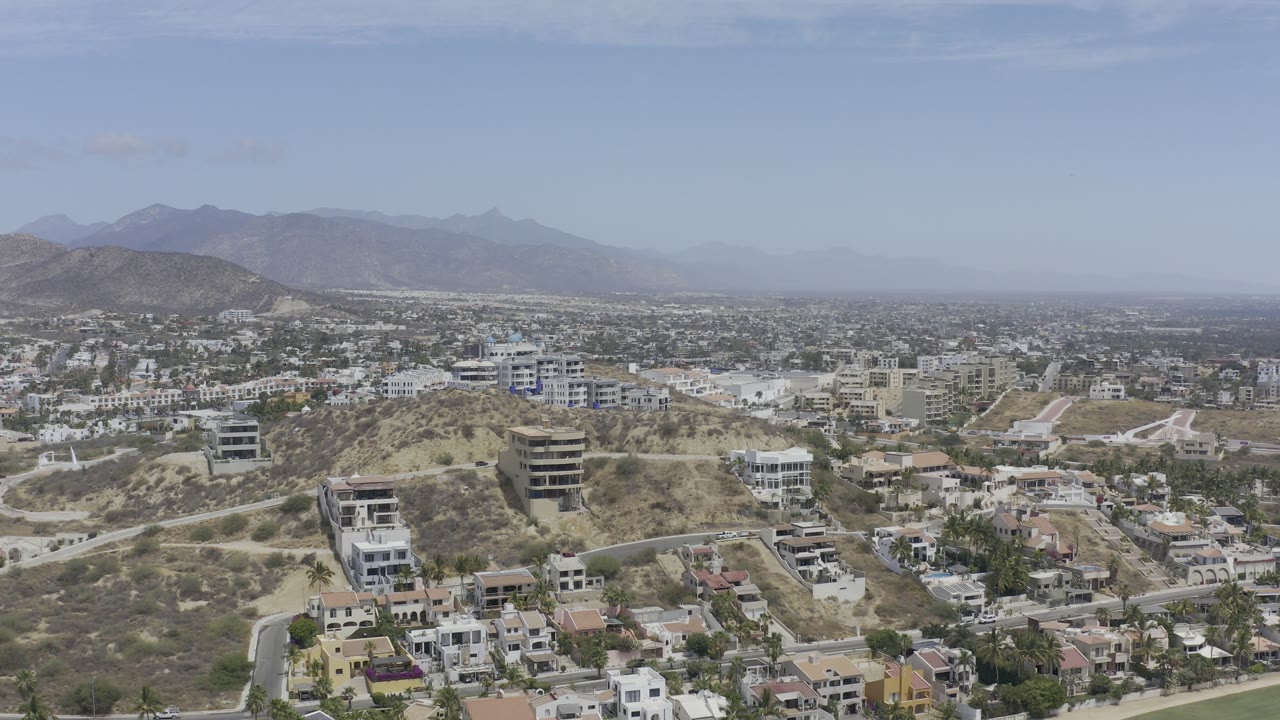 Aerial view of modern hillside buildings and sprawling city beyond.
