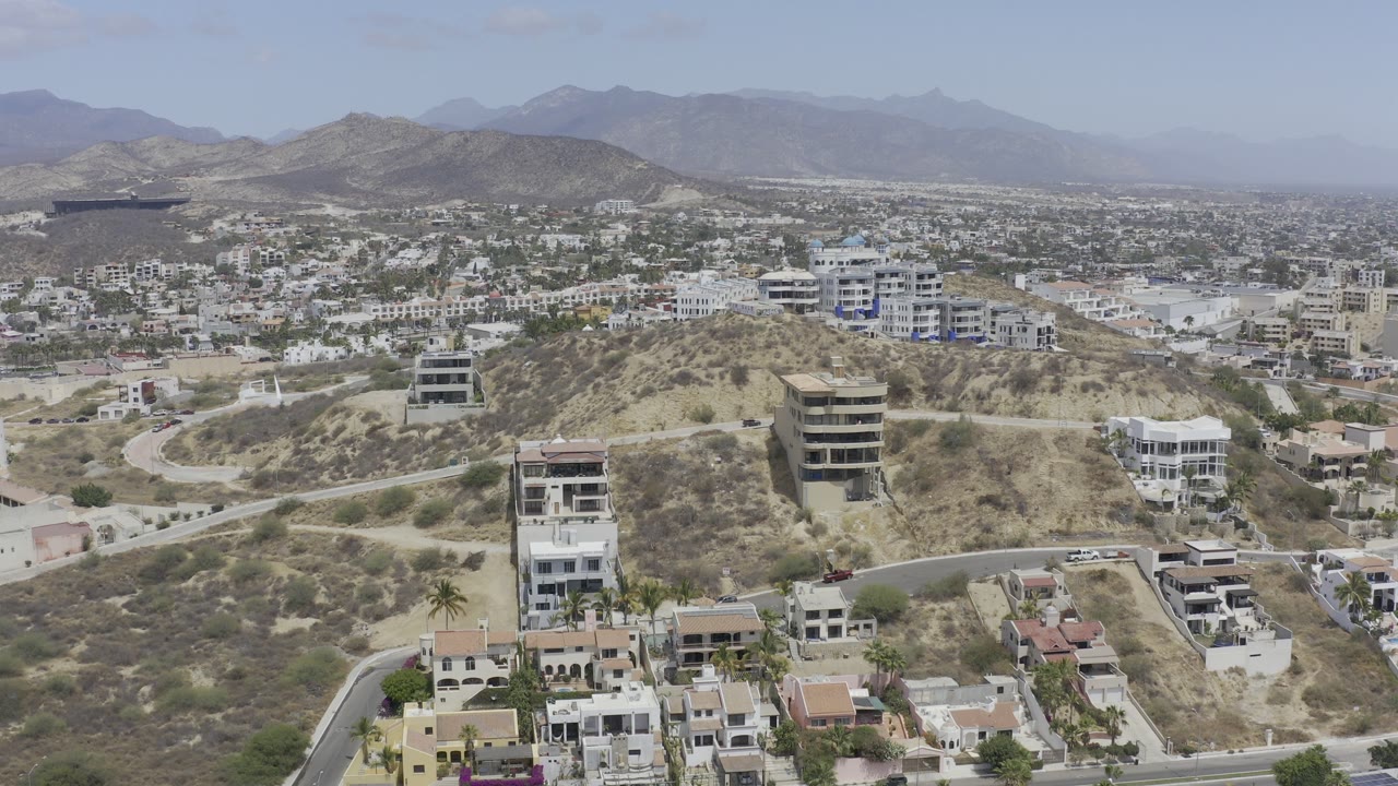 Aerial view of dry hillside homes and distant mountains.