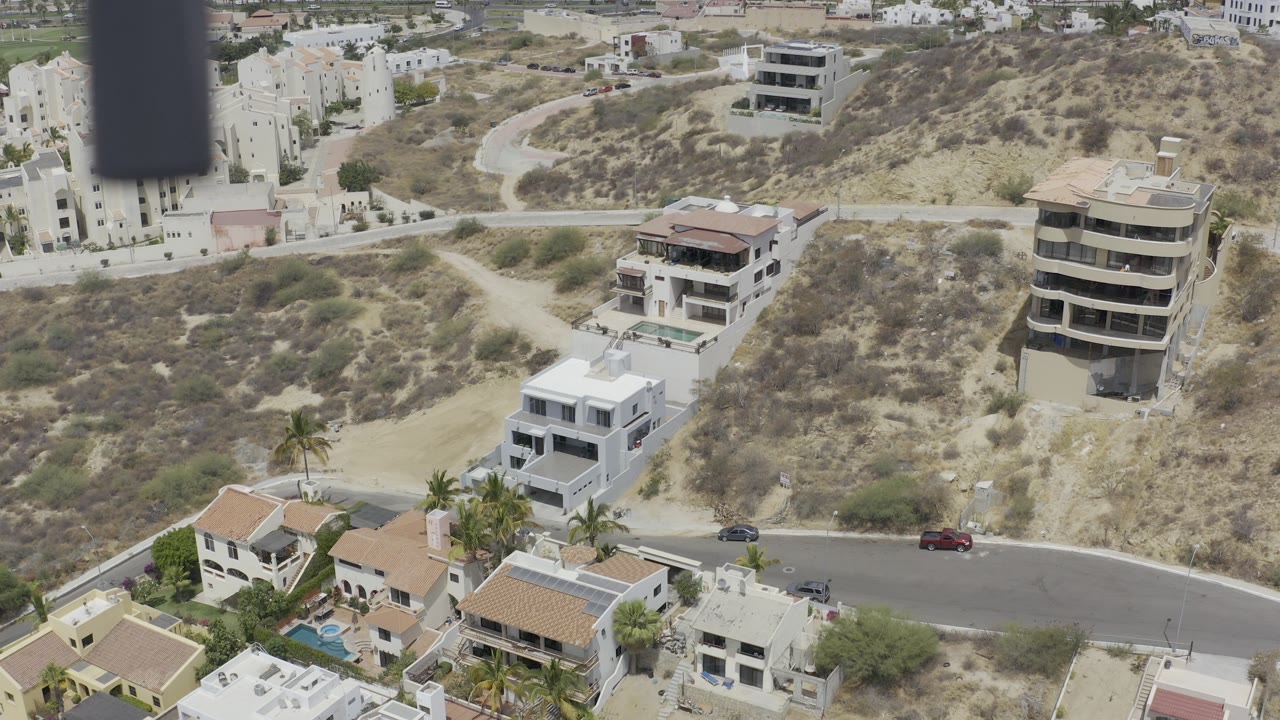 Aerial view of hillside homes and a curved residential road.
