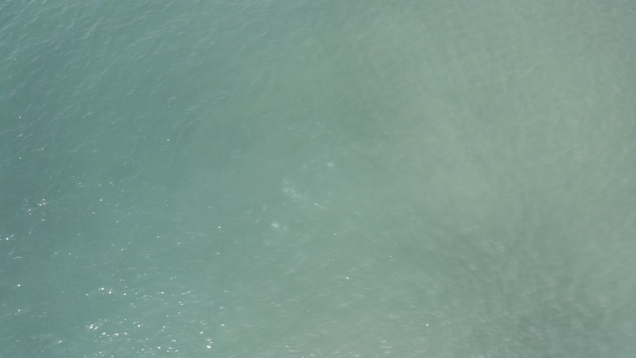 Blue-green ocean surface in Los Cabos, Mexico, seen from above with slightly brighter glints across the middle and no visible people.