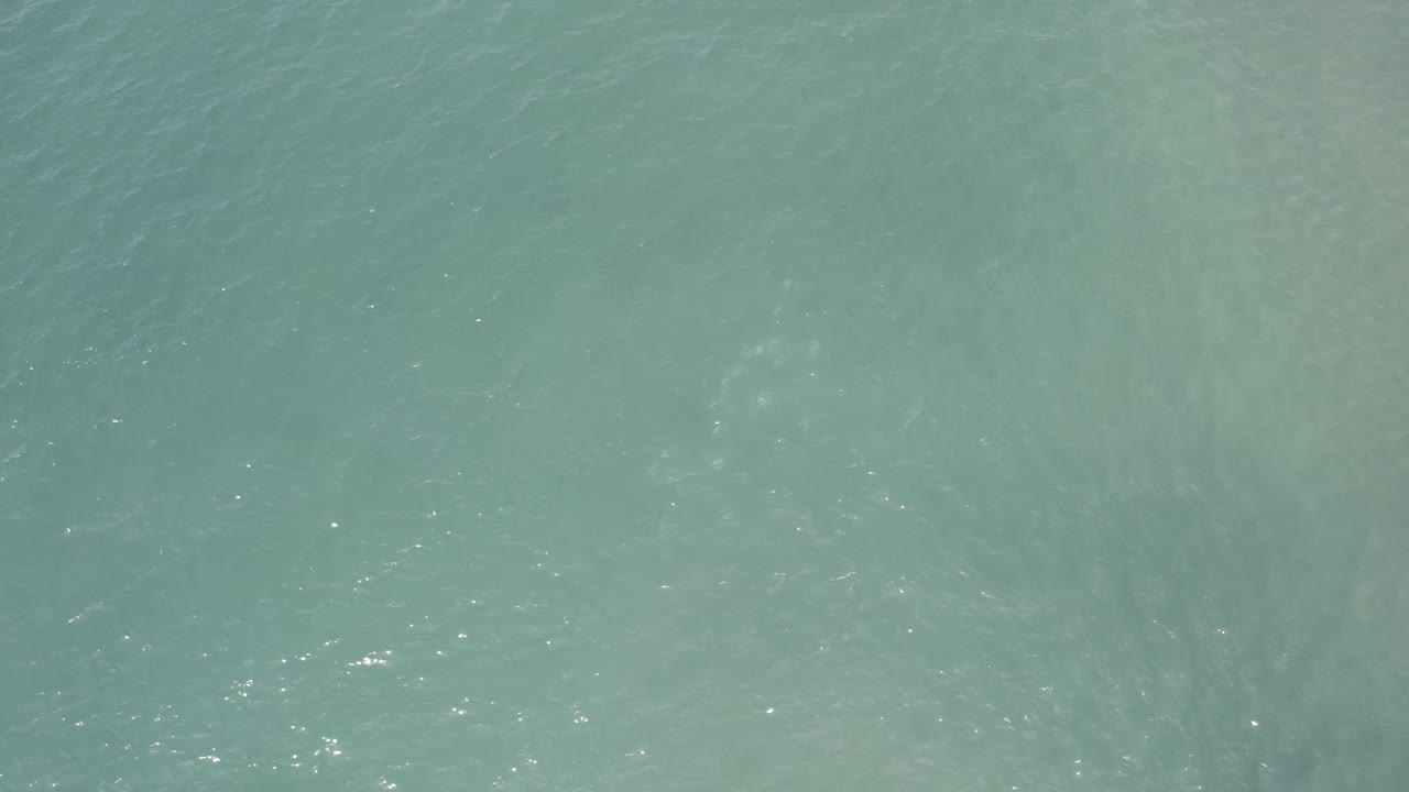Blue-green water in Los Cabos shows brighter scattered reflections across the rippled surface, with no visible people.