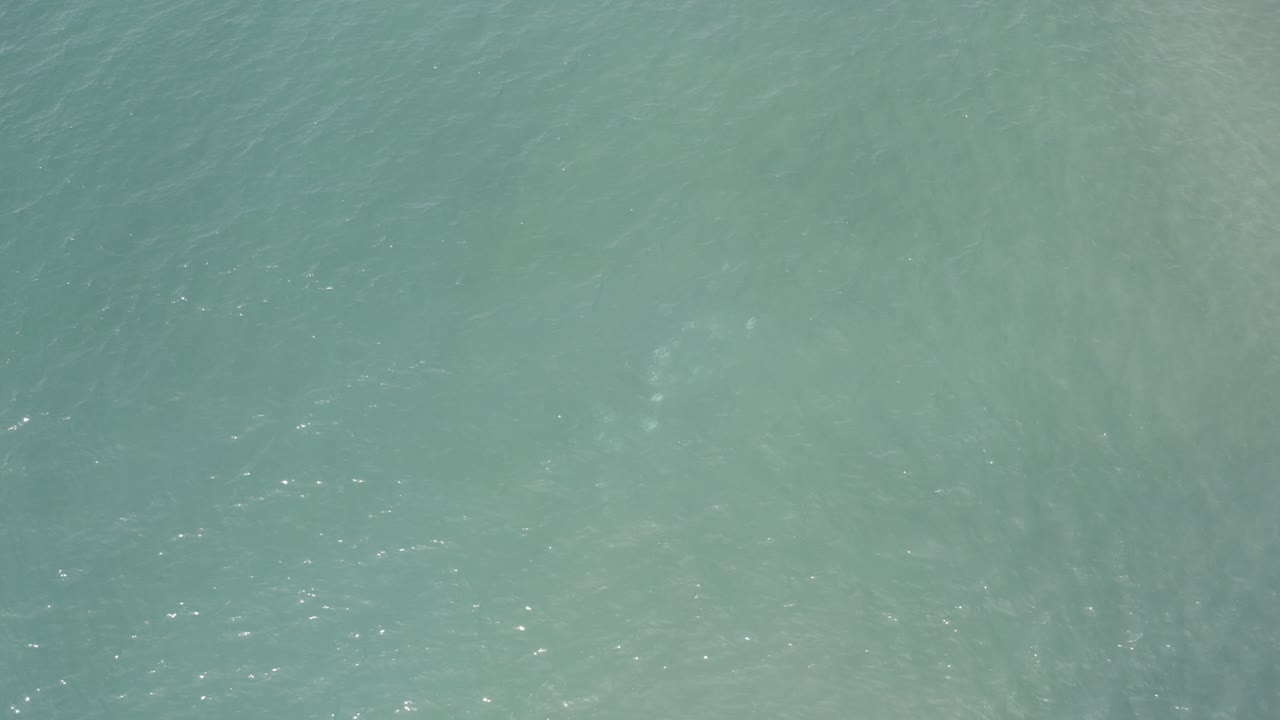 Pale turquoise ocean texture with cloudy motion under the surface.