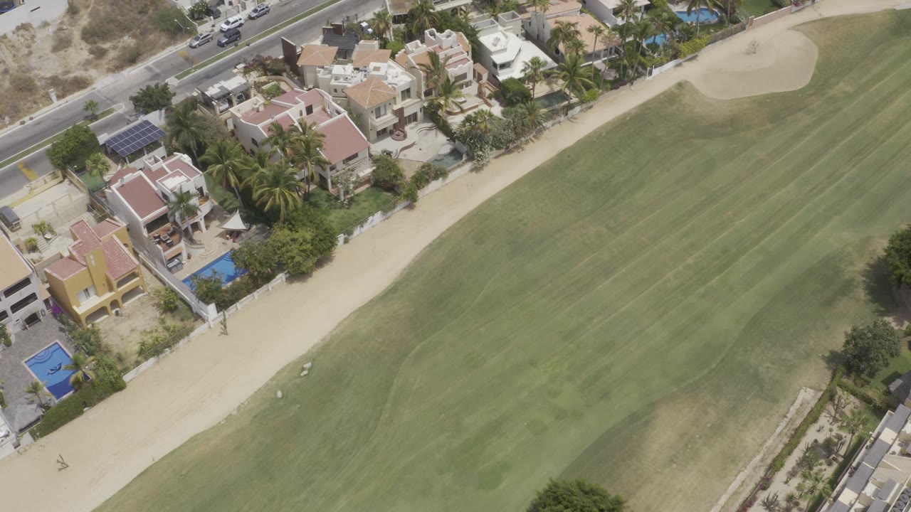 Aerial view of houses beside a green golf fairway.