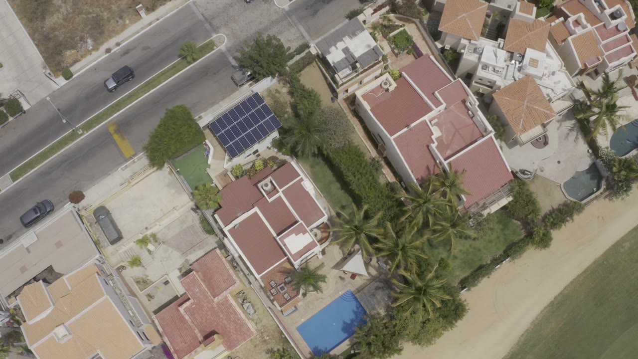 Overhead view of a road, homes, palm trees, and shoreline.