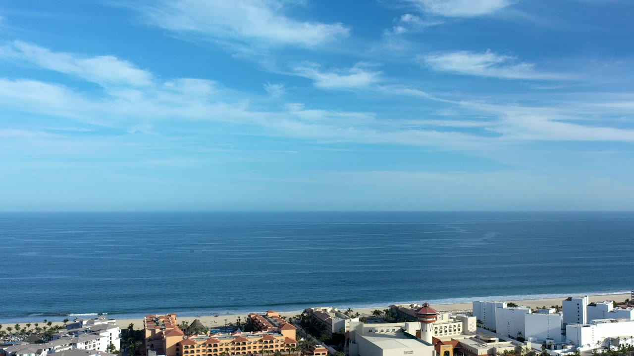 Wide aerial view of blue ocean, beach, and oceanfront buildings