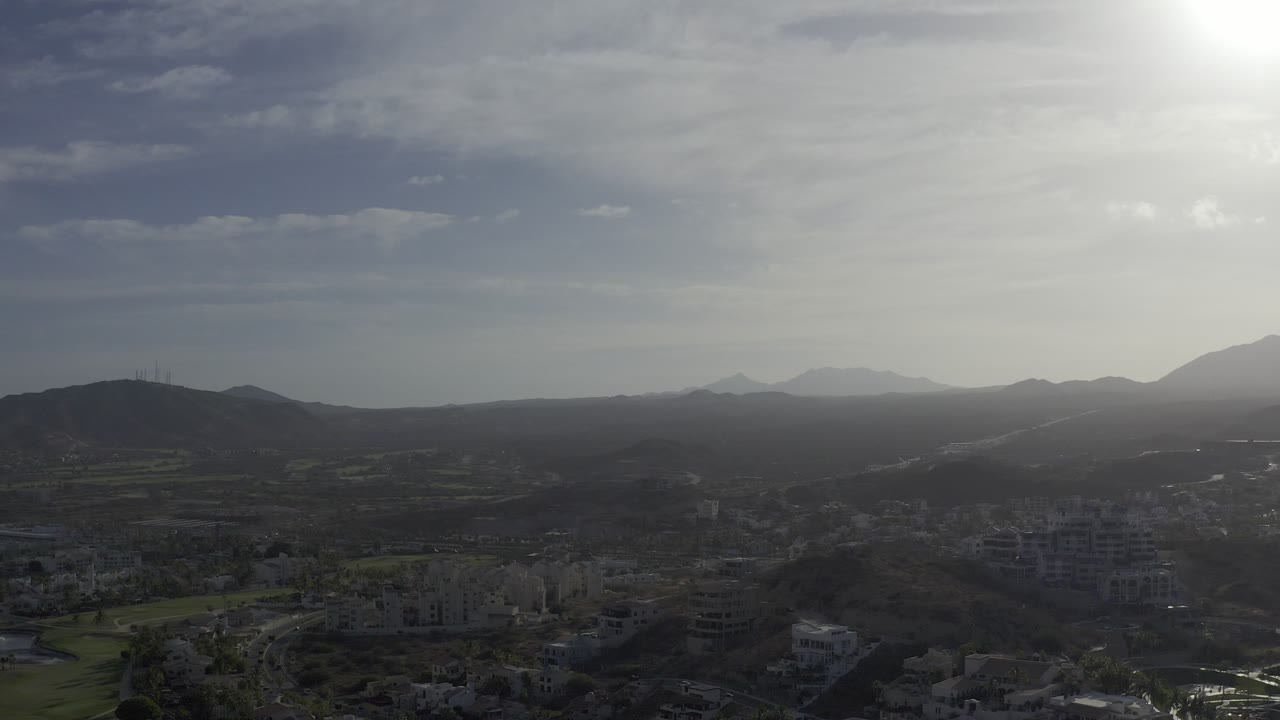 Road and low buildings below a bright mountain horizon