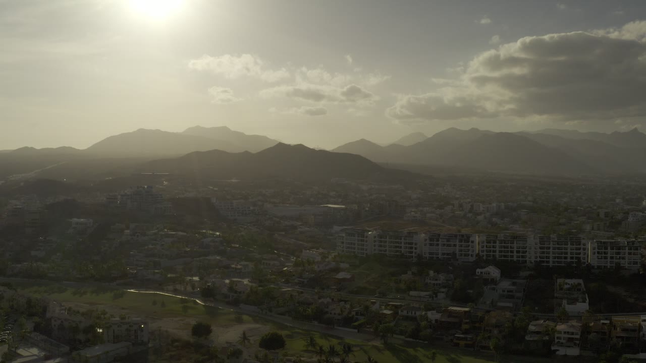 City and low hills beneath a bright hazy sky.
