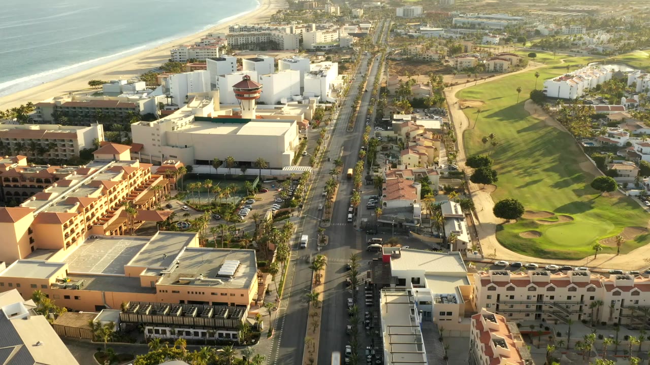 Aerial view of hotels, road, golf course, beach, and ocean.
