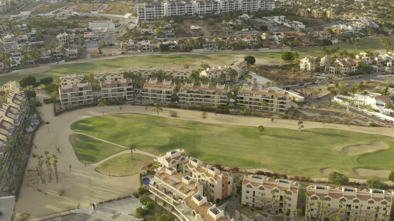 Aerial view of apartment buildings beside a green golf fairway.