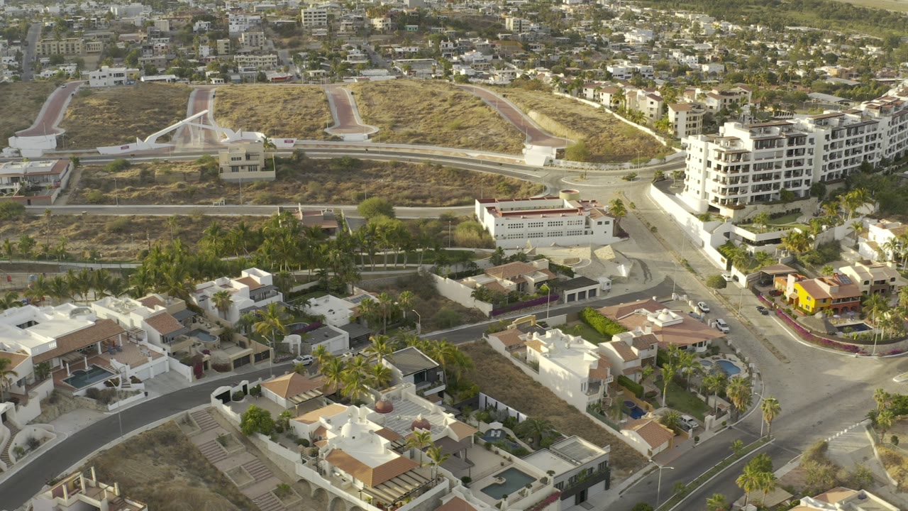 Aerial view of homes, roads, palm trees, and dry lots.