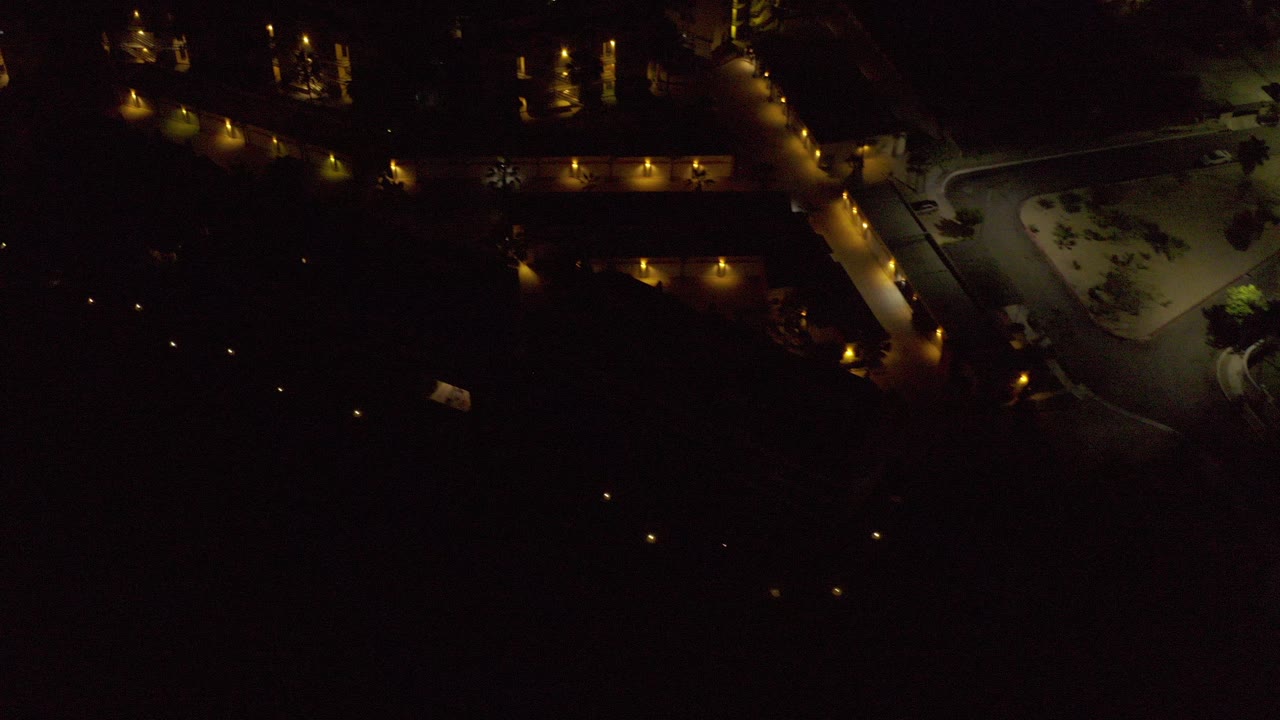 Dark aerial view of lit roads and buildings at night