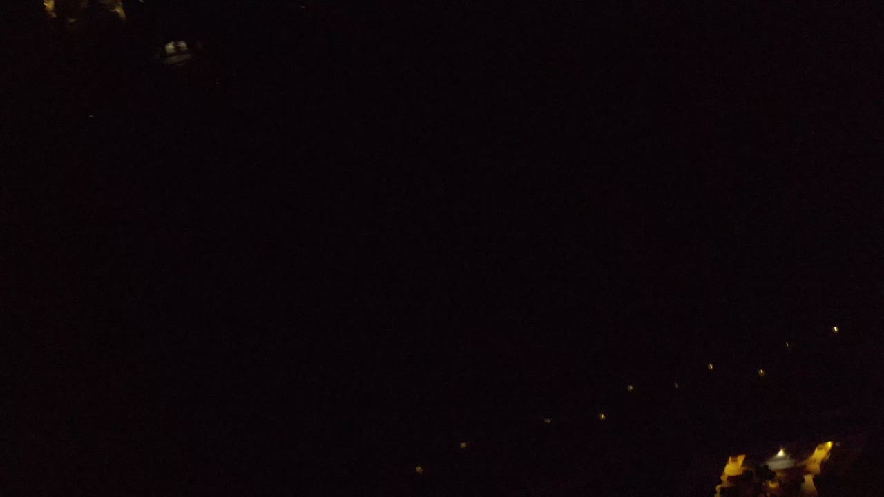 Nighttime Los Cabos aerial frame showing a small cluster of illuminated residential buildings surrounded by mostly black open space, with no visible people.