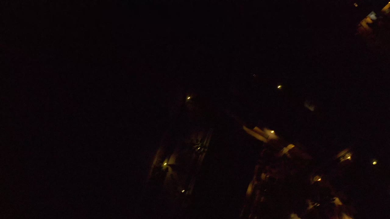 A bird's-eye nighttime frame over Los Cabos, Mexico, where faint roads and warm light clusters appear against a mostly black landscape with no visible people.