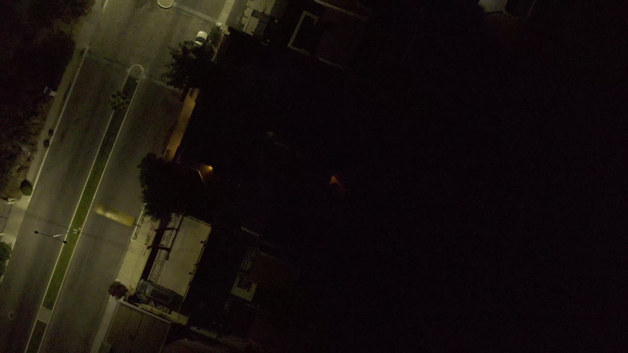 Top-down night street view with a lit curb lane and dark surrounding lots