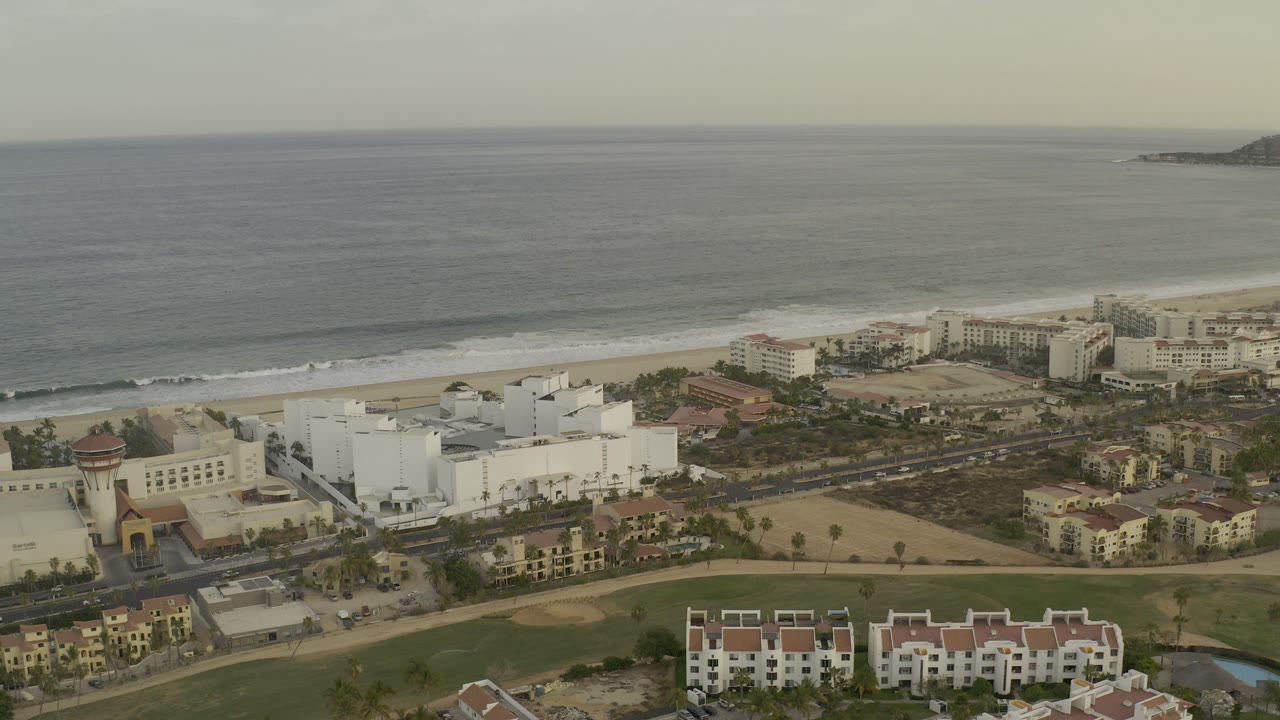 Aerial view of beachfront buildings beside a gray-blue sea.