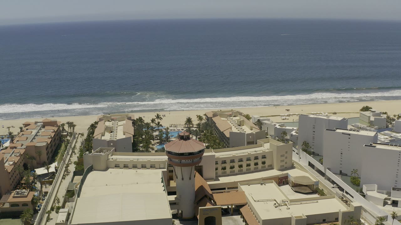 Aerial view over beachside buildings, roadways, sand, and ocean