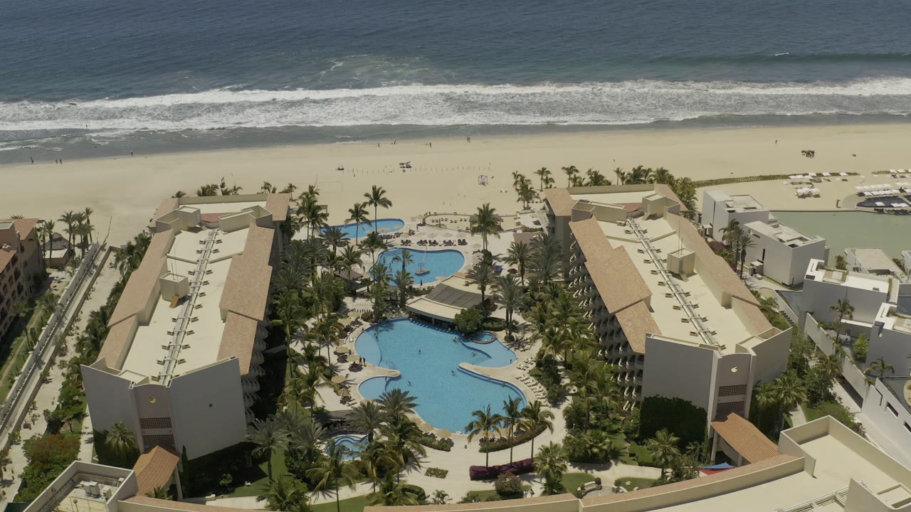 Beachfront resort with pools, palms, sand, and ocean horizon