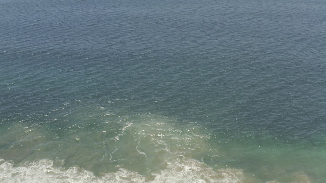 Wide ocean surface with surf entering from the lower left.