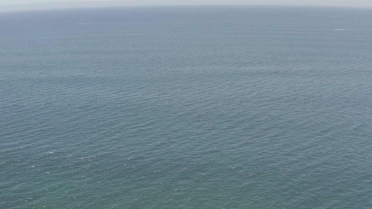 Wide ocean surface under a pale horizon.