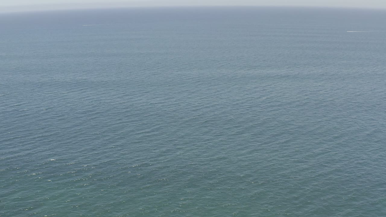 Open Los Cabos ocean surface with fine ripple texture, muted blue green color, pale sky, and no visible people.
