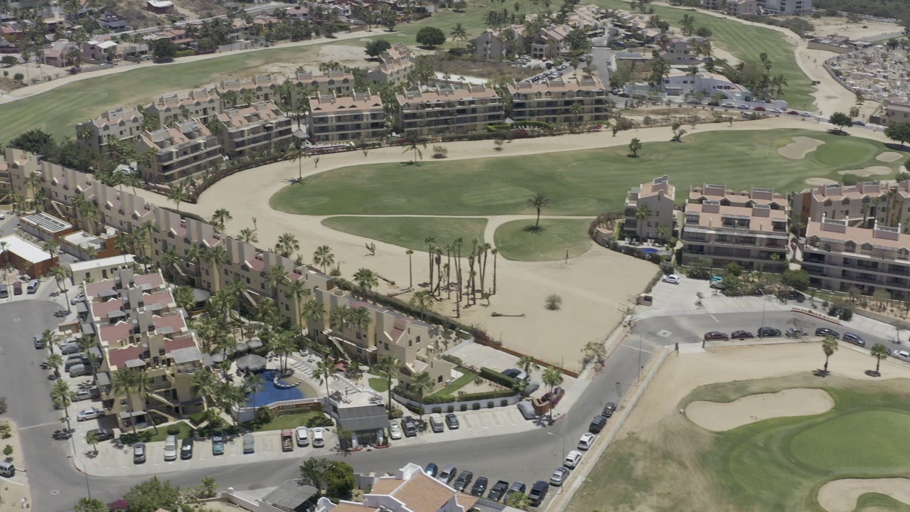 Aerial view of golf course fairways beside resort buildings and roads.