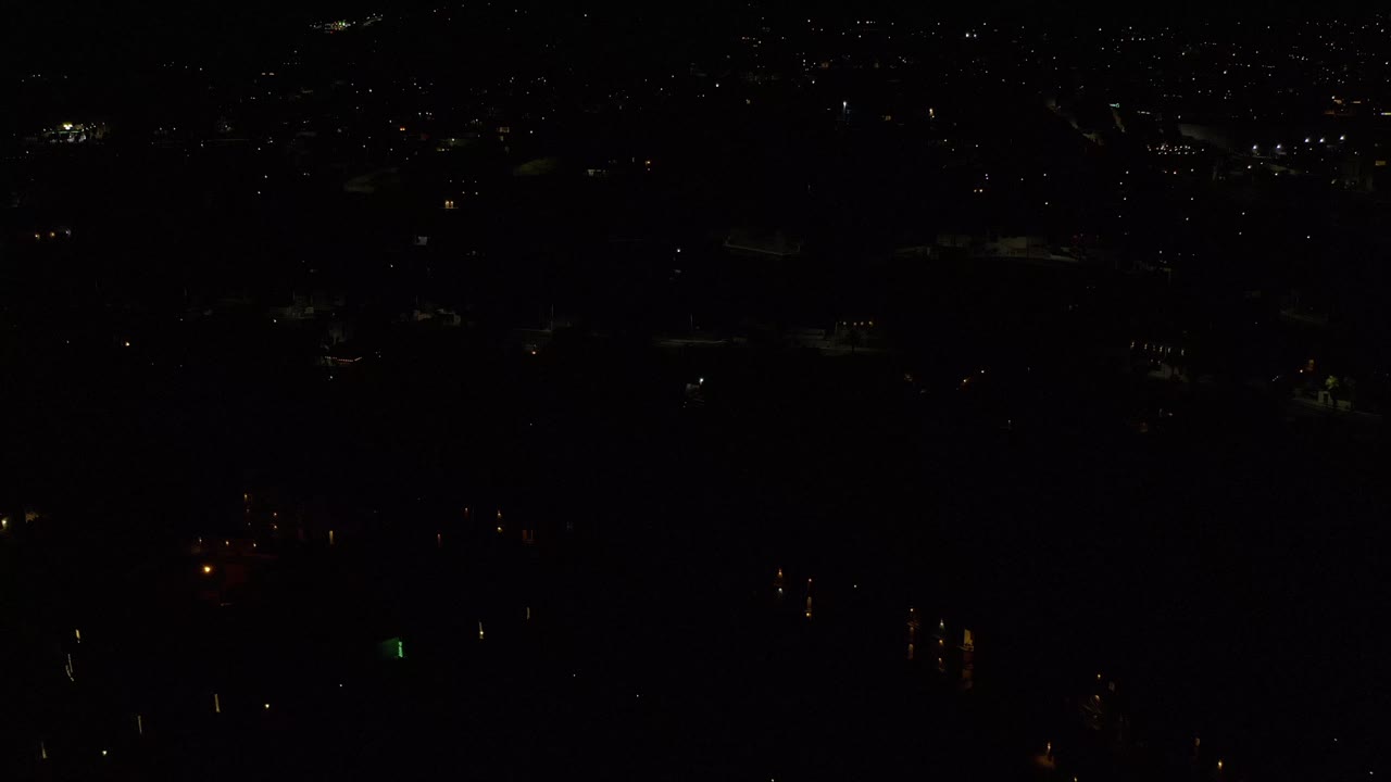 Los Cabos at night with tiny points of light spread across a mostly black frame and no visible people.
