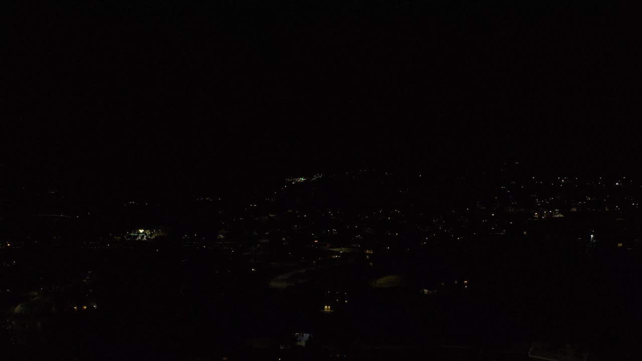 Very dark aerial city view with scattered distant lights.