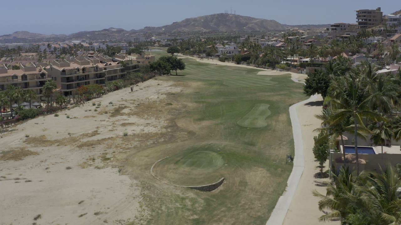 High view of a desert golf course with sand traps, palms, and resort structures.